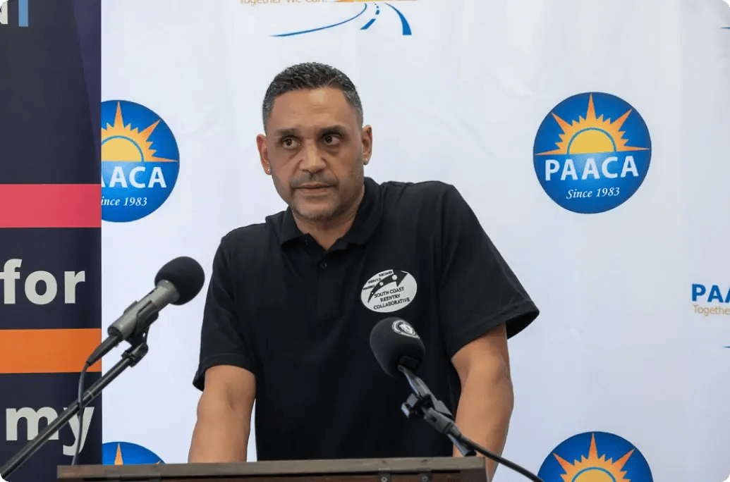 一位演讲者站在带麦克风的讲台上，在徽标和彩色横幅的背景下向听众发表演讲。